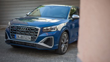 Audi SQ2 in blau, schraeg von vorn im Anschnitt in Hofeinfahrt