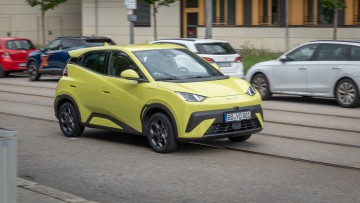 BYD Dolphin Surf in Lime Green fahrend auf einer Nebenstraße als Mitzieher fotografiert