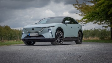 Mazda CX-6e schräg von vorn vor Wald fotografiert