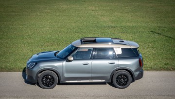 Mini Countryman Diesel in der Ausstattungslinie Favoured in 3. Generation in der Seitenansicht leicht von oben mit geöffnetem Schiebedach.