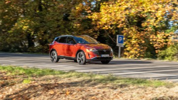 Nissan Qashqai fahrend vor Herbstbäumen