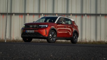 Stehend vor einer Wand von vorn fotografierter Opel Frontera in Kanyon Orange lackiert 