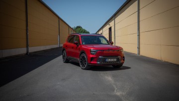 Rot lackierter Smart #5 Brabus zwischen zwei Hallen mit gelben Wänden