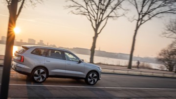 Volvo EX90 im Sonnenaufgang fahrend, direkt vor der Alster in Hamburg