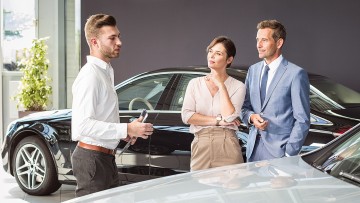 Ein Autokäufer berät eine Frau und einen Mann in einem Showroom.
