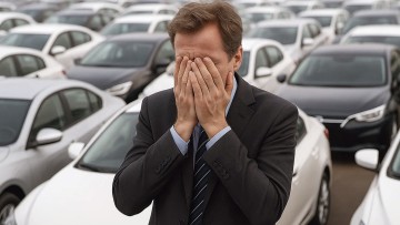 Ein Mann schlägt aus Verzweiflung seine Hände vor das Gesicht. Er steht inmitten zahlreicher Autos