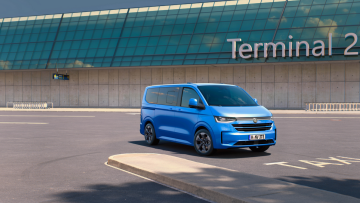 VW Caravelle (2025) in Mid Blue Metallic vor Terminal-Gebäude