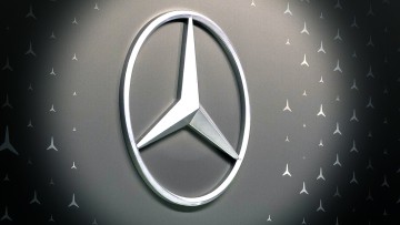 Ein großer Mercedes-Stern und viele kleine Markenlogos an einer Wand