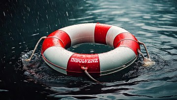 Ein Rettungsring mit der Aufschrift Insolvenz treibt im Regen auf dem Wasser.