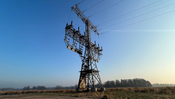 Ein Strommast steht mit Brandspuren auf einem Feld nahe der Tesla-Autofabrik. In der Autofabrik in Grünheide steht die Produktion wegen eines Stromausfalls nach einem Brandanschlag auf den Hochspannungsmast still.