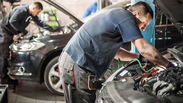 Kfz-Mechaniker arbeiten an Autos in einer Werkstatt