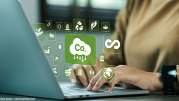 Frau sitzt vor Laptop und es sind abstrakte Symbole zur CO2-Reduktion zu sehen.