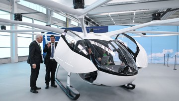 Winfried Kretschmann (Bündnis 90/Die Grünen, l), Ministerpräsident von Baden-Württemberg, und Stefan Klocke, Vorsitzender des Beirats von Volocopter, schauen sich einen Volocopter an. 