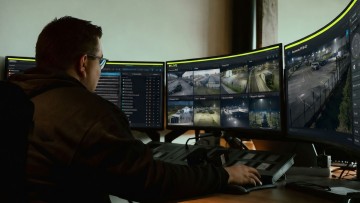 Person vor vielen Bildschirmen