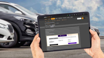 Händler hält ein Tablet mit Alpha Online Software vor seine Gebrauchtwagen