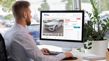 Händler sitzt am Schreibtisch vor seinem Desktop und ersteigert ein Fahrzeug über AUTO1.com