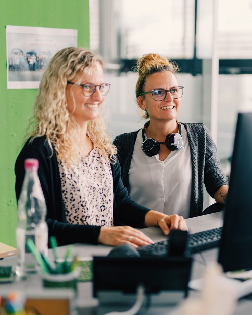 Zwei GETTYGO Mitarbeiterinnen stehen gemeinsam vor einem PC