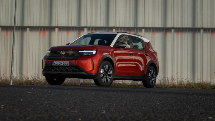 Stehend vor einer Wand von vorn fotografierter Opel Frontera in Kanyon Orange lackiert 