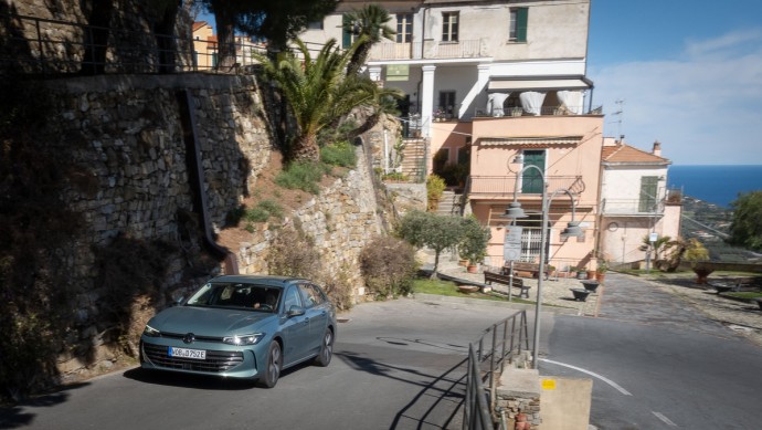 VW Passat in Grünmetallic fährt den Berg in einer Ortschaft hinauf.