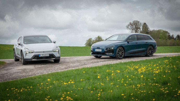 Audi A6 Avant e-tron vs. Polestar 4 Audi A6 Avant e-tron und Polestar 4 stehen von vorn fotografiert auf einer Anhöhe bei bewölktem Himmel.
