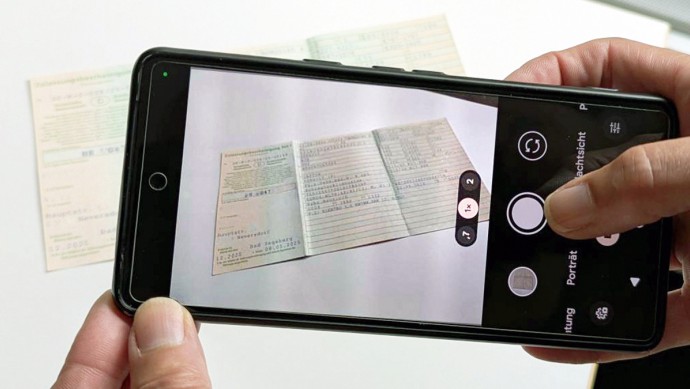 AlphaController-KI: Händler fotografiert mit dem Smartphone einen Fahrzeugschein