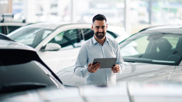 Gebrauchtwagen-Verkäufer mit Tablet im Showroom