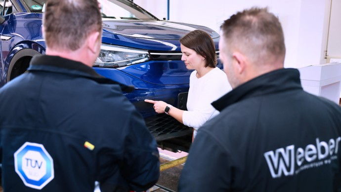 Mitarbeiter von TÜV SÜD und Autohaus Weeber mit Kundin am Fahrzeug