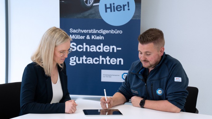 TÜV SÜD Sachverständiger in einer Besprechung mit einer Autohaus-Kundin