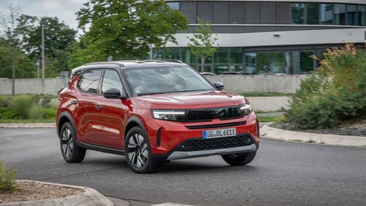 Opel Frontera Electric in der Standardlackierung Kanyon Orange Metallic fährt um Kreisverkehr