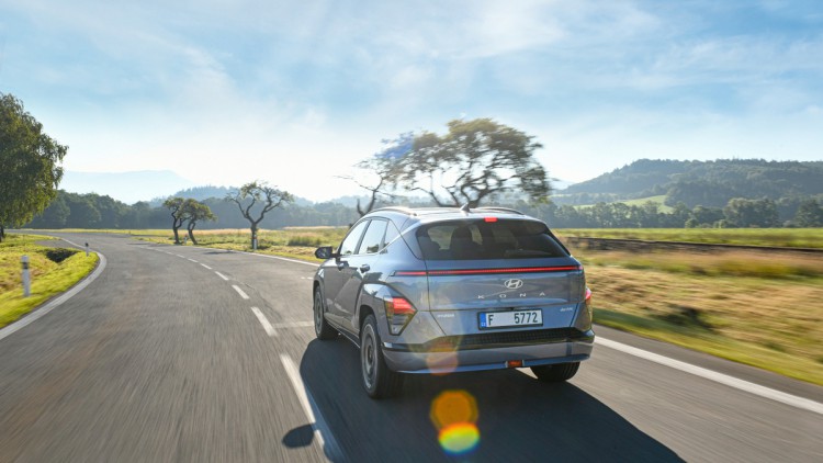 Hyundai Kona-e auf Landstraße fahrend, Aufnahme von hinten Car to Car