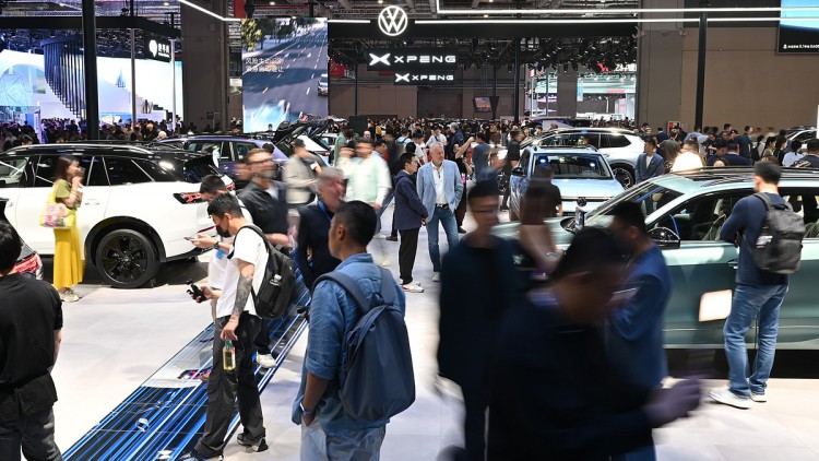 Menschen laufen über den Messestand der Marke Volkswagen.