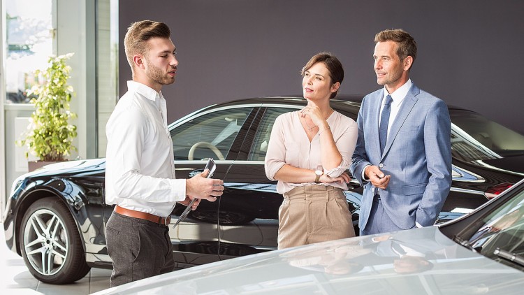Ein Autokäufer berät eine Frau und einen Mann in einem Showroom.