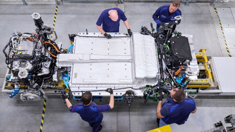 BMW-Mitarbeiter montieren die Kühlwasserleitungen für die Motor-Getriebeeinheit des BEV-Modells iX1.