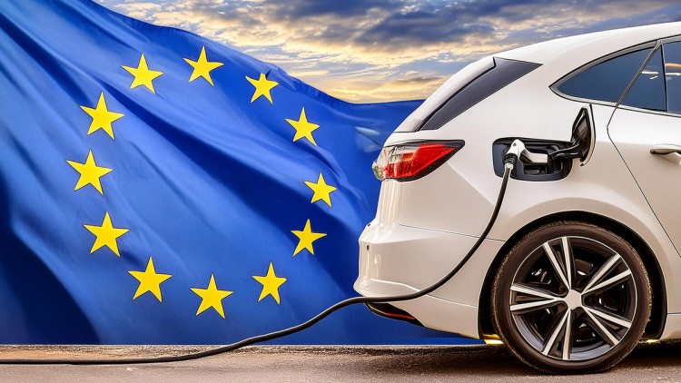 Weißes Elektroauto mit Ladestecker vor EU-Flagge