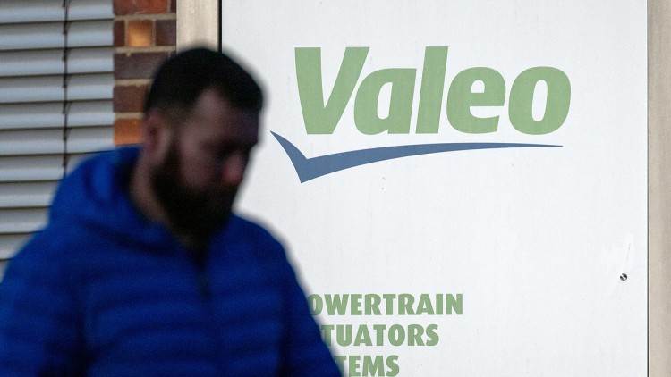 Ein Mann läuft mit gesenktem Kopf vor einem Schild mit dem Logo des Automobilzulieferers Valeo vorbei. (zu dpa: «Valeo baut weitere Stellen ab») 