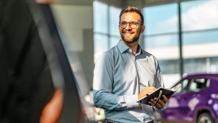 Mann in Autohaus mit mobilem Endgerät