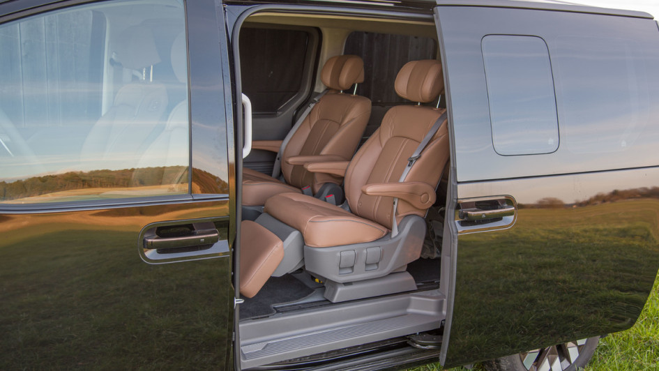 Hyundai Staria Signature AWD Business-Class in der zweiten Sitzreihe. Sitze mit braunem Leder bezogen. Foto durch die geöffnete Seitentür