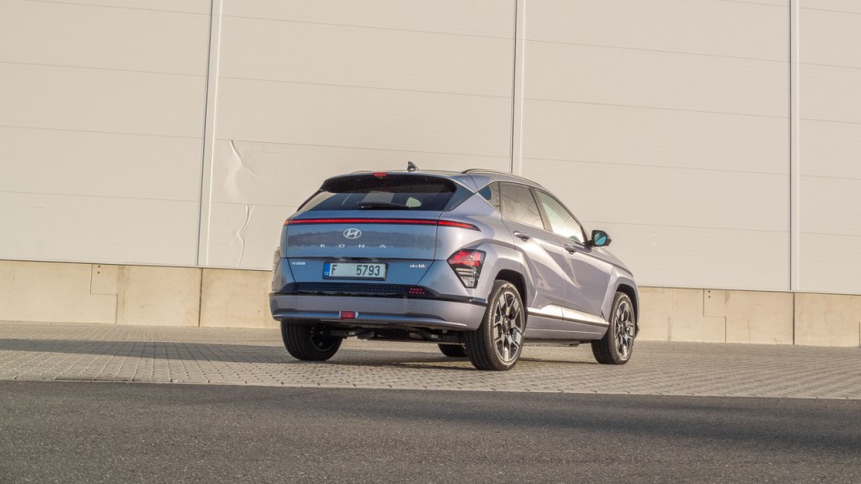 Hyundai Kona electric schreaeg von hinten fotografiert vor einem Fabrikgebäude