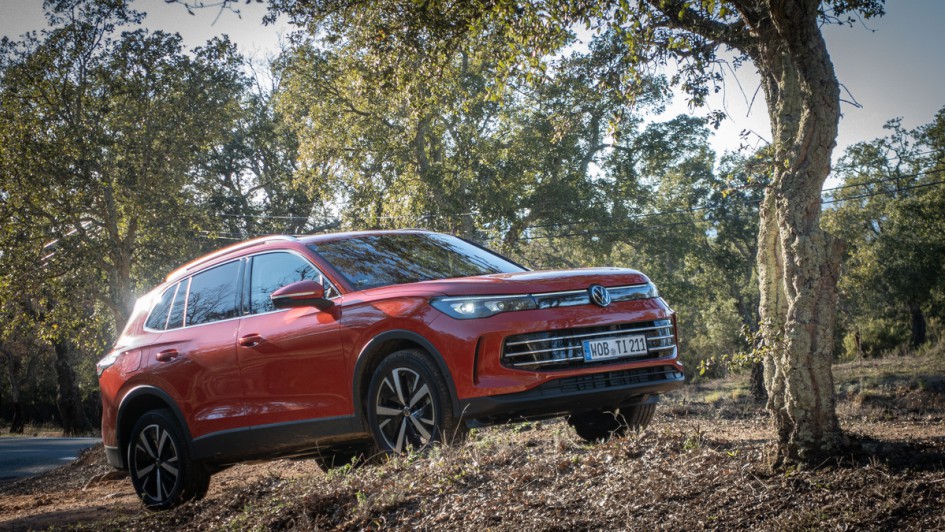Roter VW Tiguan auf Waldweg neben Baum stehend schraeg von vorn fotografiert