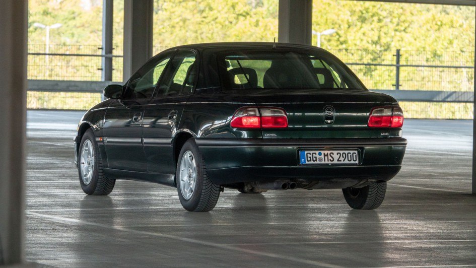 Dschungelgrüner Opel Omega MV6 in Garage von hinten fotografiert, Rückleuchten eingeschaltet