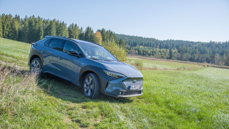 Subaru Solterra steht auf einer Wiese mit Bäumen im Hintergrund