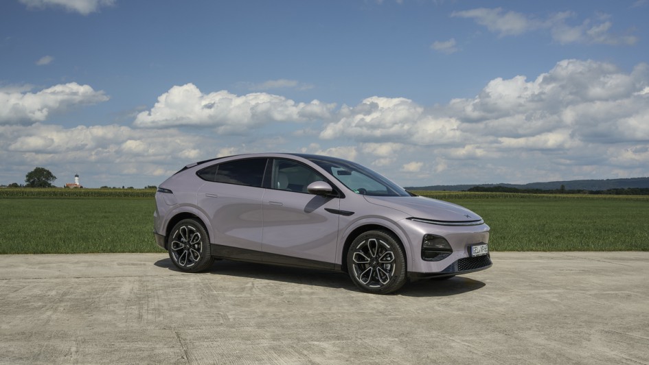 Seitenansicht des Xpeng G6 stehend auf Asphalt vor grüner Wise und blauem Himnmel