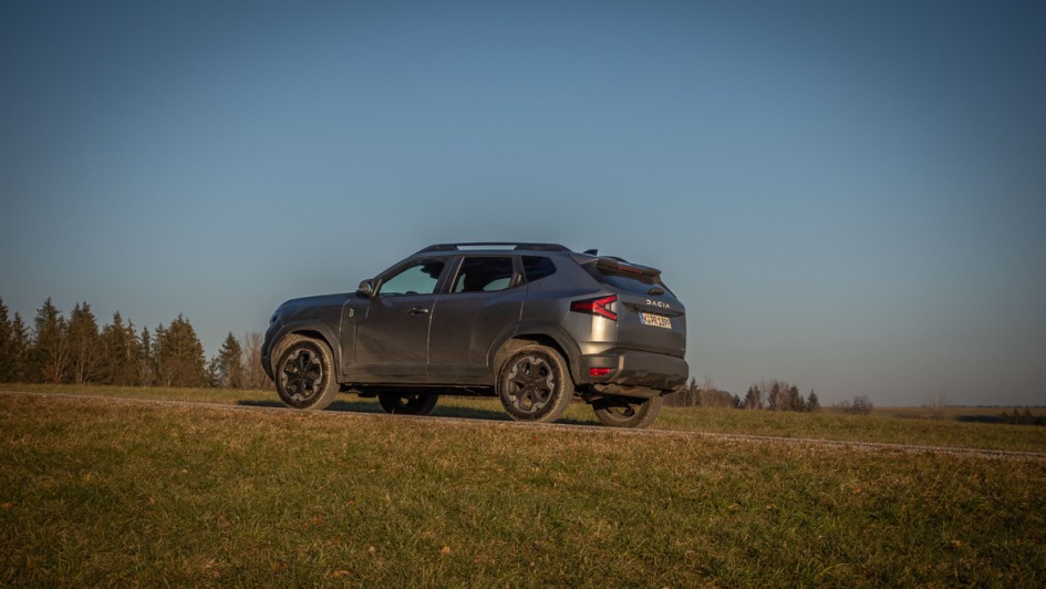 Dacia Duster schräg von hinten auf einer Anhöhe gegen den Himmel fotografiert