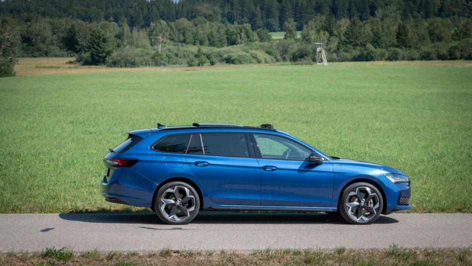 Seitenansicht des blauen Super Combi stehend auf Asphalt vor einer grüßen Wiese.