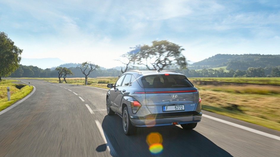 Hyundai Kona-e auf Landstraße fahrend, Aufnahme von hinten Car to Car