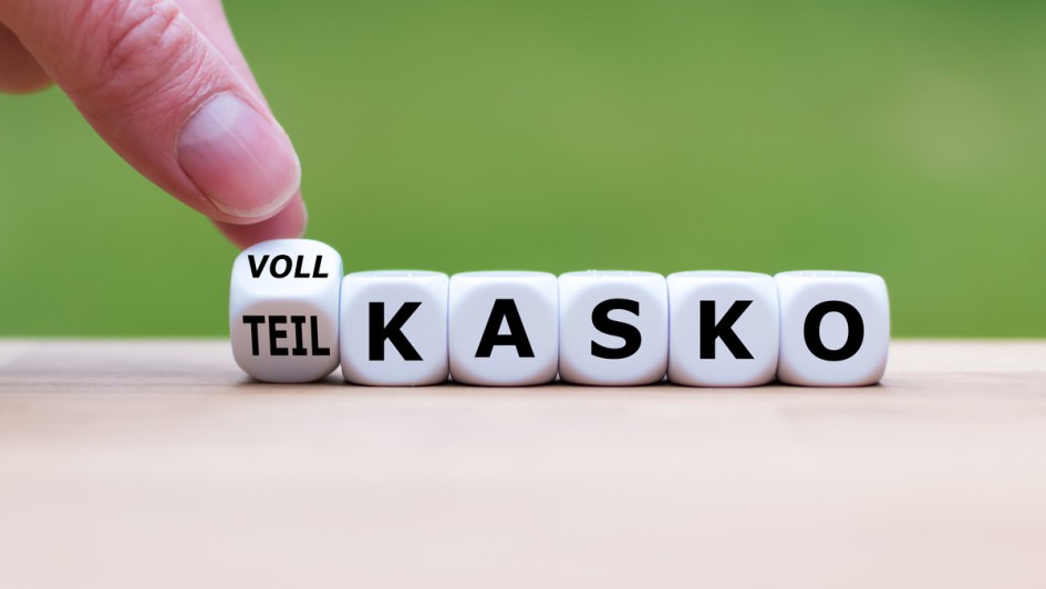 Hand dreht einen Würfel und ändert das Wort "Teilkasko" in "Vollkasko"